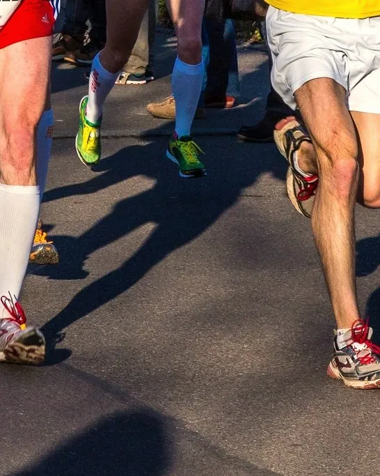 Marathon runners mid-stride on a sunny road
